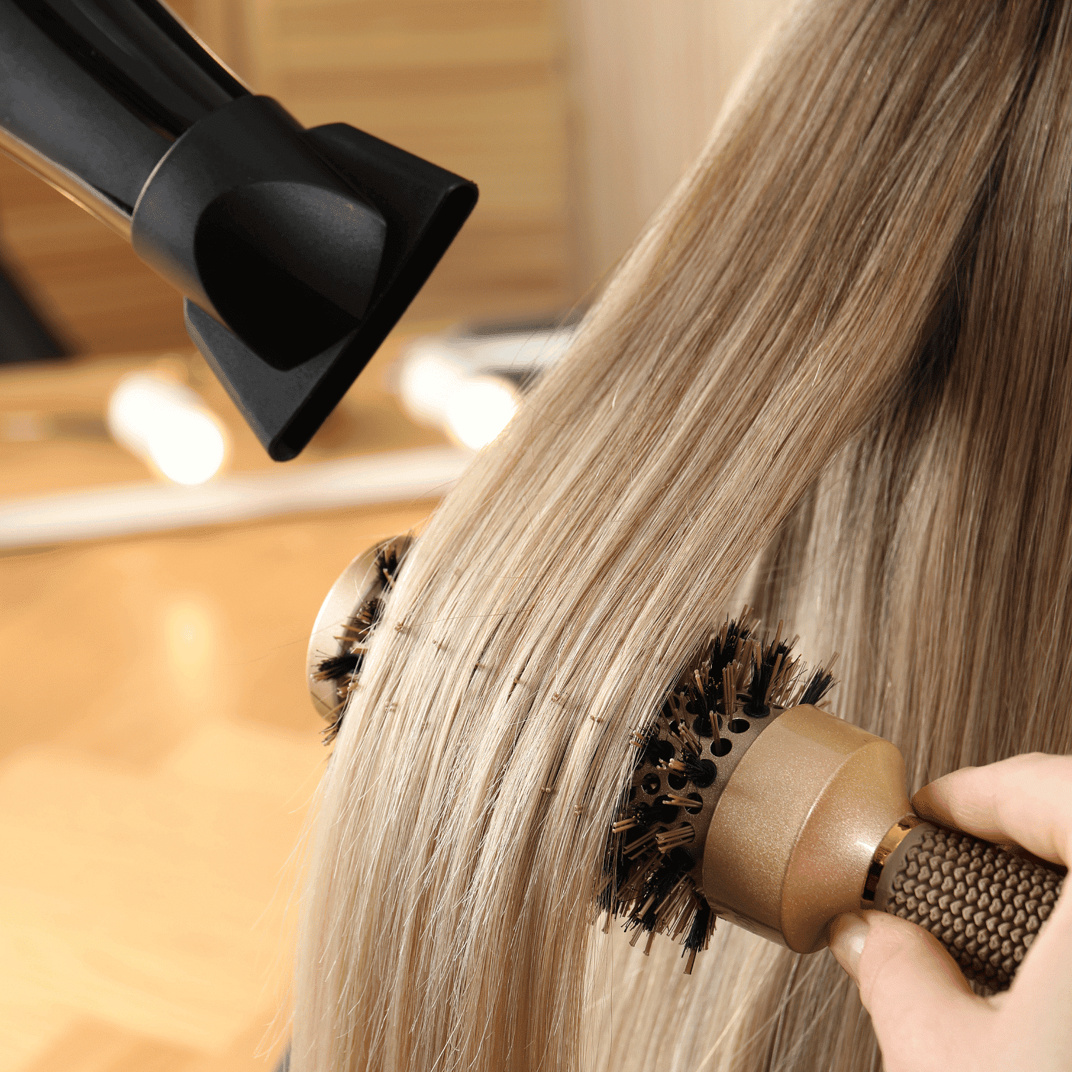 Blow-drying long, straight blonde hair with a round brush in a salon.