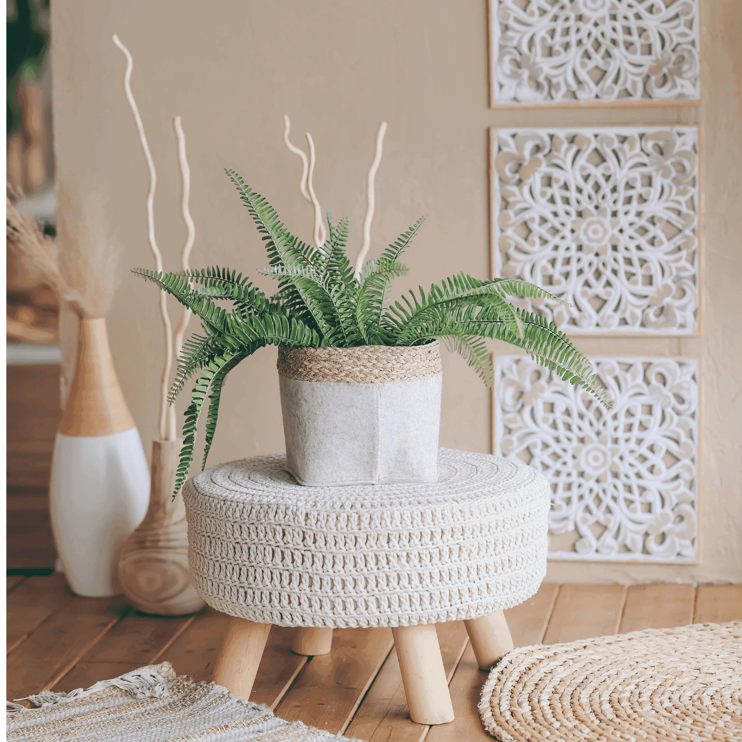 Potted fern on a woven stool with decorative panels in a stylish, earthy room setting.